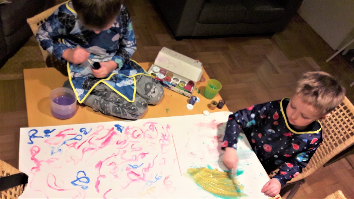 dwóch chłopców ubranych w kolorowe fartuszki maluje farbami